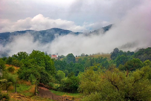 Wunderschöne Berglandschaft mit alleinstehendem Gebäude und Nebel über dem Berg