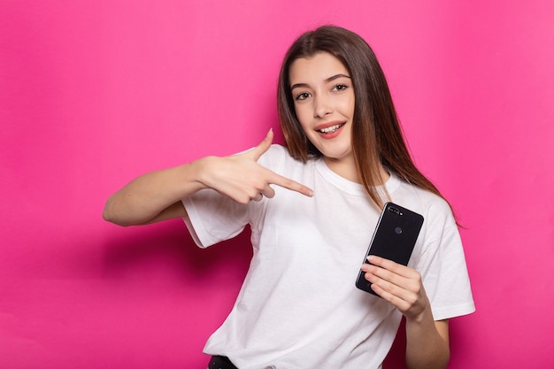 Wunderschöne, bezaubernde, gut aussehende Dame mit ihrem brünetten Haar mit offenem Mund und starren Augen, sie trägt ein urbanes, trendiges, stilvolles, lässiges Outfit, das auf einem lebhaften rosa Hintergrund isoliert ist