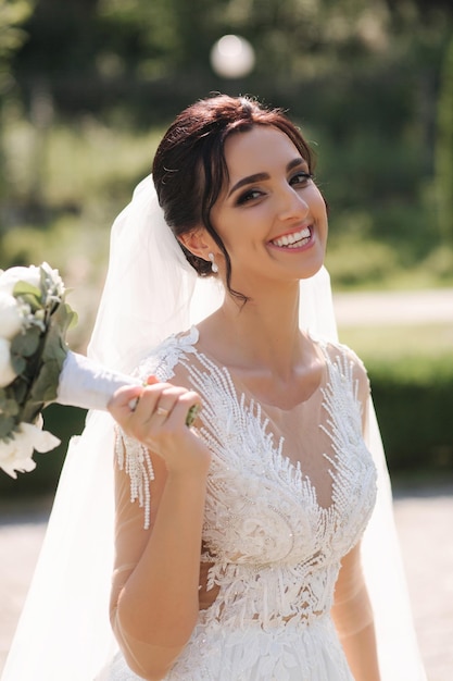 Wunderschöne Braut im eleganten Hochzeitskleid mit einem Strauß weißer Blumen an ihrem Hochzeitstag