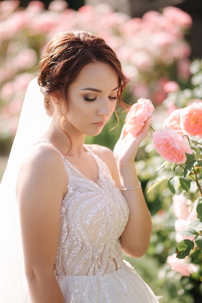 Wunderschöne Braut im eleganten Kleid im Freien. Model von rosa Blumen