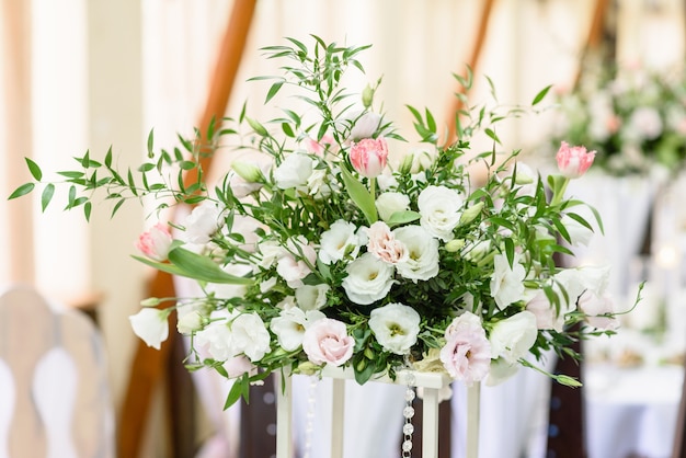 Wunderschöne florale Kompositionen im Restaurant für die Hochzeitszeremonie. Feierliche Zeremonie des Bemalens des Bräutigams und der Braut