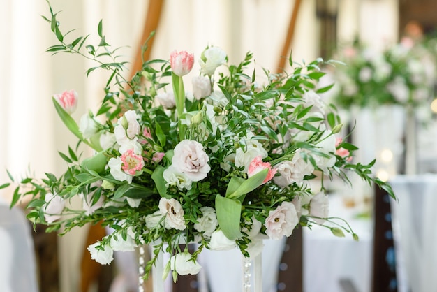 Wunderschöne florale Kompositionen im Restaurant für die Hochzeitszeremonie. Feierliche Zeremonie des Bemalens des Bräutigams und der Braut