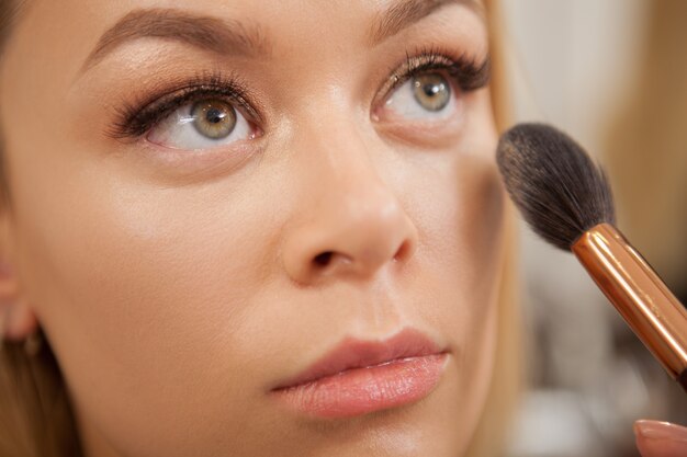 Wunderschöne Frau, die professionelles Make-up bekommt