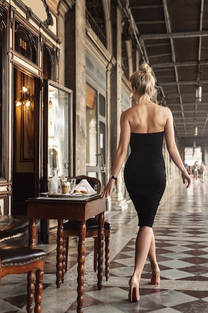 Wunderschöne Frau trägt ein schwarzes Kleid in einem italienischen Vintage-Café