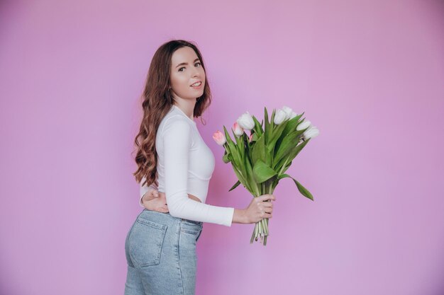 Wunderschöne junge Dame, die sich freut, einen Strauß Tulpen zum Frauentag zu erhalten