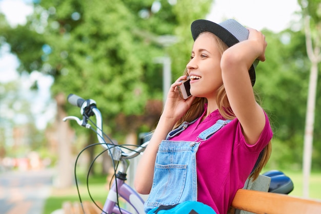 Wunderschöne junge Frau, die aufgeregt schaut, während sie am Telefon spricht, das sich im örtlichen Park entspannt gute Nachrichten Emotionen Glück Schönheit Erholung Freizeit sorglose Mobilitätstechnologie Träger Kommunikation.