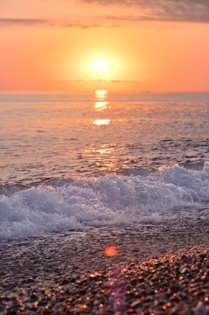 Wunderschöne Landschaft mit hellem Sonnenuntergang über dem Meer. Meereswelle und Küste in goldener Stunde
