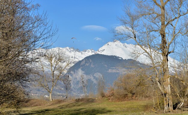 wunderschöne landschaftliche Landschaft in alpinen, schneebedeckten Bergen mit Paragliding weit weg im Himmel