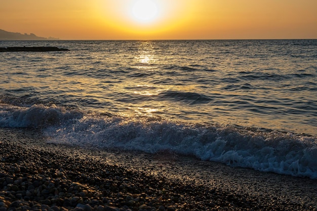Wunderschöne Meer Sonnenuntergang Landschaft Spiegelreflexion der Morgendämmerung auf nassen Kieselsteinen Goldenes Sonnenlicht über Meereswellen Nahaufnahme von Gezeitenschaum und Meereskieselküste