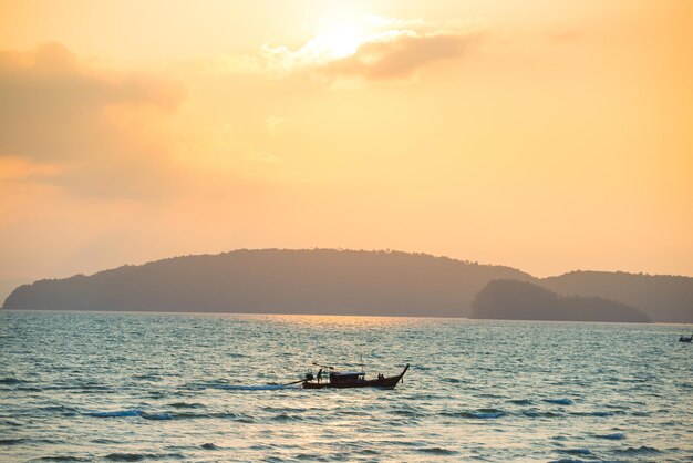 Wunderschöne Meereslandschaft mit kleinem Boot, blauer Küste und farbenfrohem Sonnenuntergang mit strahlender Sonne
