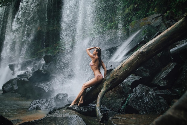 Wunderschöne nasse Frau posiert neben dem mächtigen Wasserfall Phnom Kulen