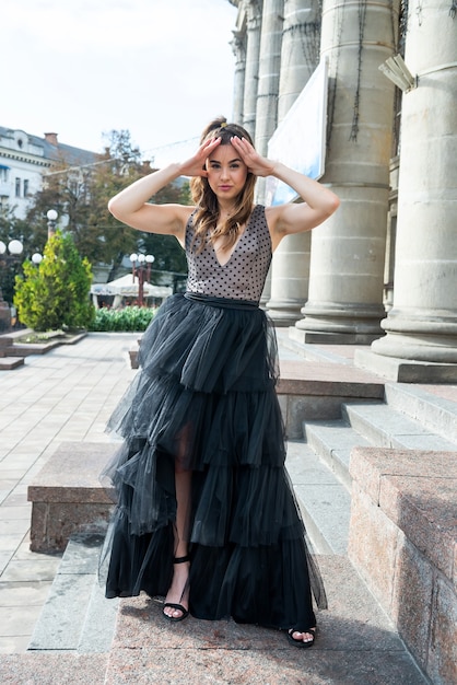 Wunderschöne sexy Frau in einem schwarzen Kleid, auf der Treppe stehend