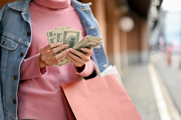 Wunderschöne und reiche Frau, die beim Einkaufen im Einkaufszentrum ihr Bargeld zählt, beschnittenes Bild