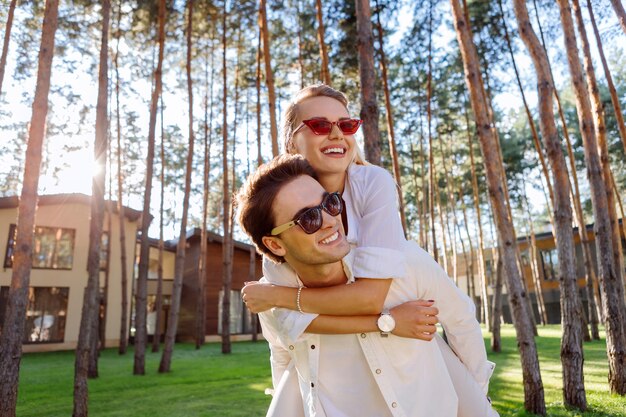 Wunderschönen Tag. Fröhliche positive Frau, die ihren Ehemann umarmt, während sie sich zusammen mit ihm glücklich fühlt