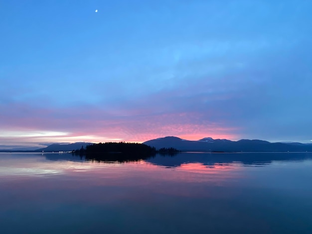 Wunderschöner rosafarbener Sonnenuntergang über den Bergen auf Vancouver Island mit Spiegelung auf dem Wasser