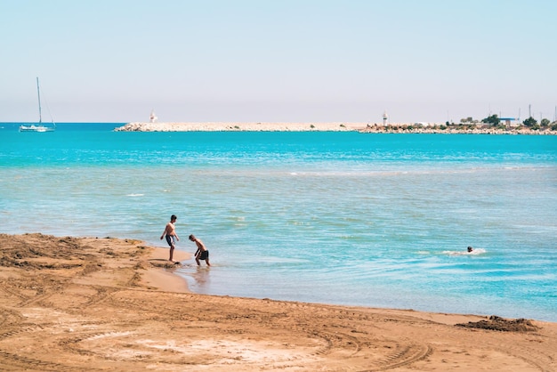 Wunderschöner Sandstrand und Menschen, die im blauen Meer schwimmen