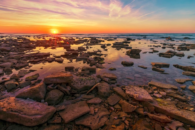 Wunderschöner Sonnenaufgang über dem Meer. Viele Felsen vorne