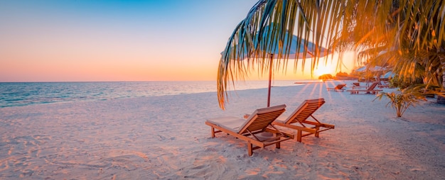 Wunderschöner tropischer Sonnenuntergang paar Stühle Liegestühle Regenschirm unter Palme Romantischer Urlaub