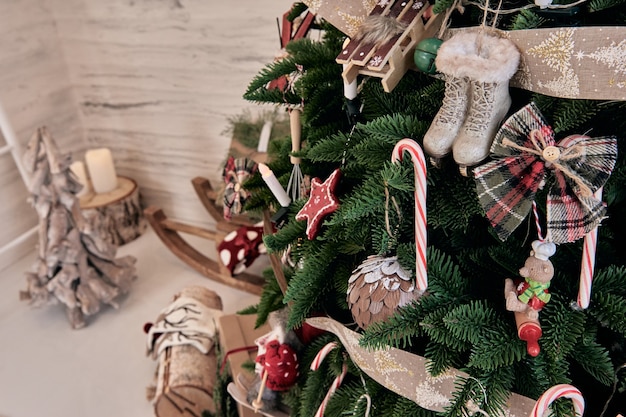 Wunderschöner Urlaub DIY handgemachte Heimtextilien. Gemütliches Zimmer mit Kerzen und Weihnachtsbaum mit Geschenken darunter. Heißgetränk auf dem Tisch. Neujahrsinterieur in einem Fotostudio