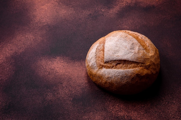 Wunderschönes, frisch gebackenes, rundes Weißbrot auf dunklem Betonhintergrund