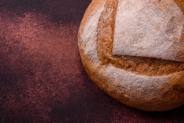 Wunderschönes, frisch gebackenes, rundes Weißbrot auf dunklem Betonhintergrund