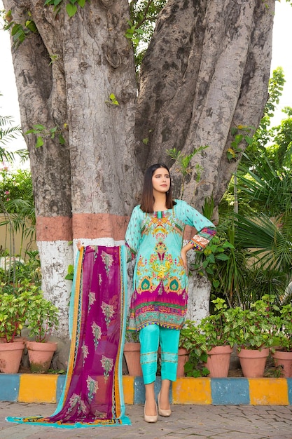 Wunderschönes Mädchen zeigt ihr Desi-Kleid und Dupatta für ein Mode-Fotoshooting im Garten