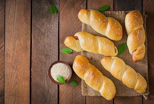 Wurst im Teig mit Sesam auf einem Holztisch im rustikalen Stil bestreut