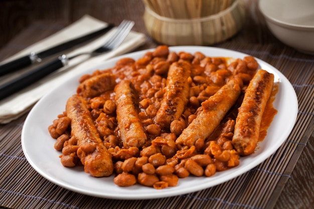 Wurst und Bohnen mit Tomatensauce auf einem Teller