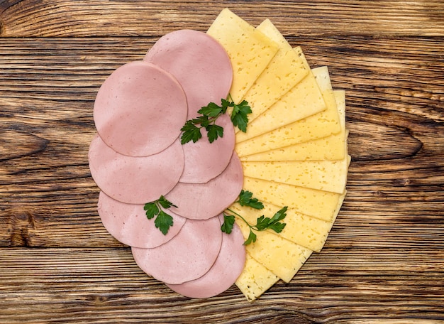 Wurst und Käse in Scheiben geschnitten auf einem hölzernen Hintergrund