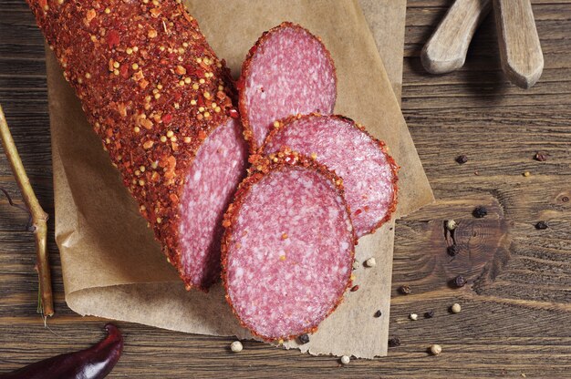 Wurstsalami mit Gewürzen auf altem Holztisch, Ansicht von oben