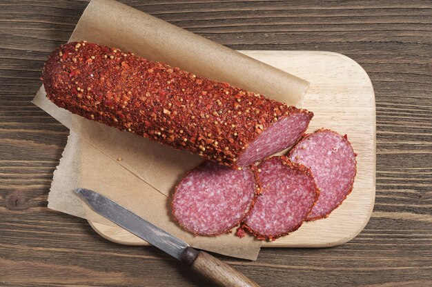 Wurstsalami mit Gewürzen auf altem Holztisch, Ansicht von oben