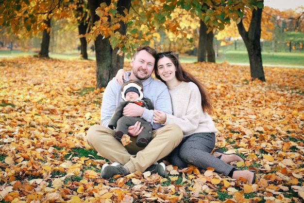 XAFamilia feliz en la naturaleza Mamá papá e hijo en el brillante paisaje otoñal sonriendo