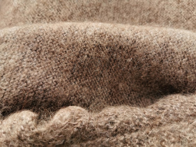 Xale de lã velho. Textura de close-up de lã marrom natural tricotada à mão. Fundo de xale de malha quente