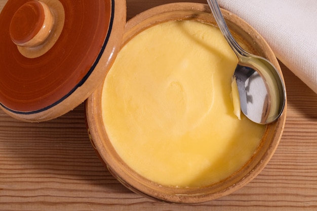 XAPure OR Desi Ghee también conocida como mantequilla líquida clarificada Pure OR Desi Ghee en cuencos de cerámica sobre una mesa de madera antigua