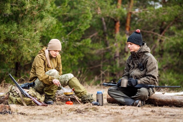 XATwo caçadores estão comendo juntos na floresta Bushcraft caça e conceito de pessoas