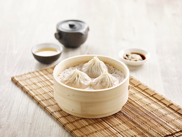 Xiao Long Bao al vapor servido en un tazón de madera aislado en la vista lateral de la alfombra sobre fondo gris