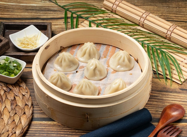 Xiao Long Tang Bao mit Holzlöffel und Serviette, serviert in einem Holzteller, Seitenansicht von taiwanesischem Essen