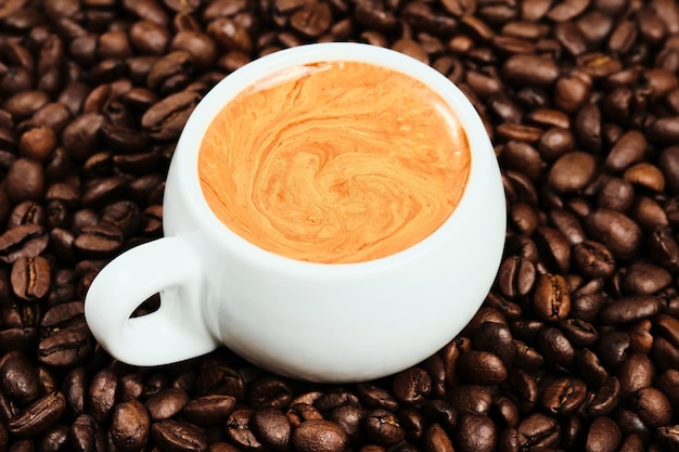 Xícara branca com café expresso e grãos de café, postura plana. fechar-se. Café italiano forte da manhã com espuma perfumada, vista superior. Ideia de café para o café da manhã