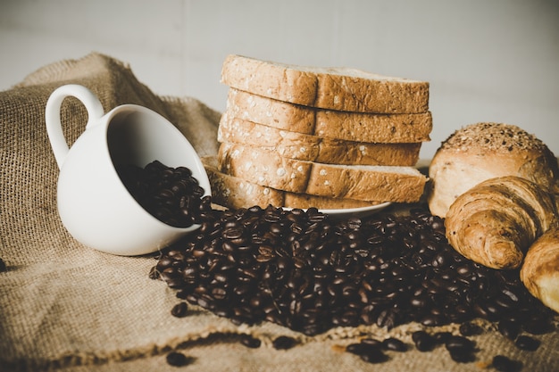 xícara branca de café de grãos com croissant e pão