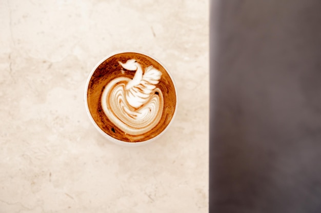 Xícara branca de cappuccino saboroso com latte art em fundo de mármore branco no café