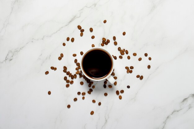 Xícara com café e grãos de café em uma mesa de mármore. Café da manhã conceito, café preto, café durante a noite, insônia. Camada plana, vista superior