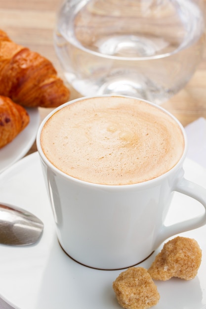 Xícara com café expresso fresco com água e croissant