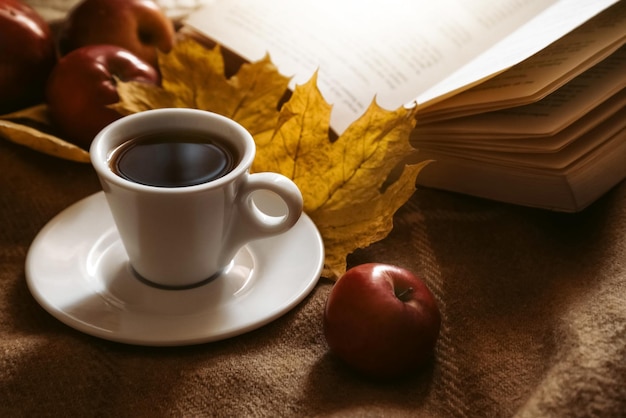 Xícara com chá de ervas perto do tempo de lazer de outono de livro aberto