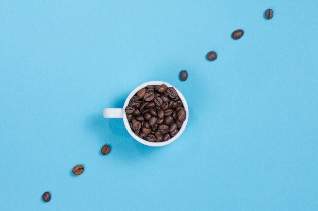 Xícara com grãos de café em uma parede colorida