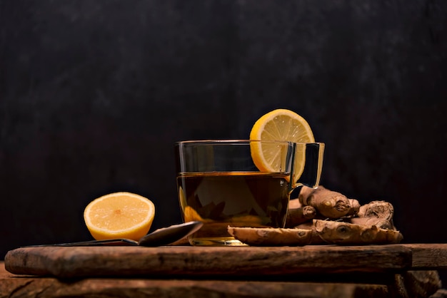 Xícara com infusão de gengibre quente em uma mesa branca com raiz de gengibre fatiada em uma tigela vista superior