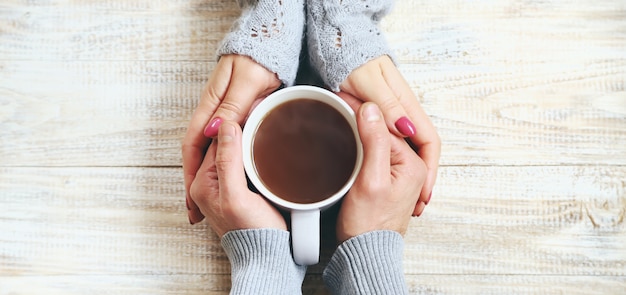 Xícara de bebida no café da manhã nas mãos dos amantes.