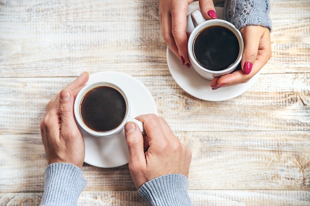 Xícara de bebida no café da manhã nas mãos dos amantes.