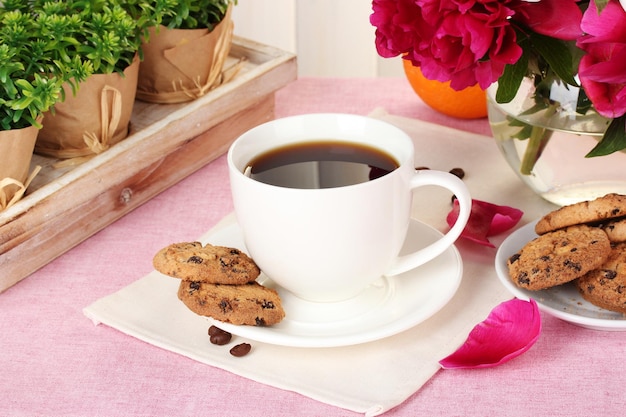 Xícara de biscoitos de café laranja e flores na mesa no café