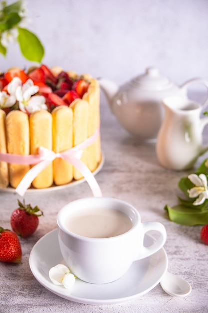 Xícara de bolo de leite com morangos frescos com ramo de flores de macieira