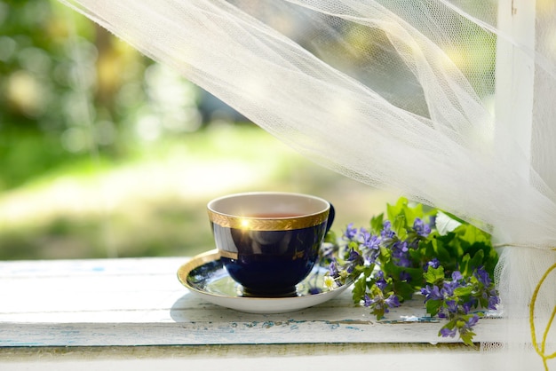 Xícara de buquê de flores de chá na mesa de madeira branca ao ar livre. Fundo desfocado do jardim de flores silvestres de chá